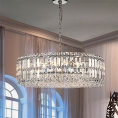 a crystal chandelier hanging from a ceiling in a room with curtains and windows