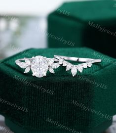 an engagement ring in a green velvet box with diamonds on the side and leaves around it