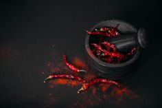 some red chili peppers in a black bowl on a dark surface with sprinkles