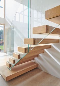 a wooden stair case with glass railing and handrail