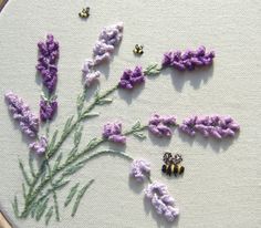 lavender flowers and bees are embroidered onto a white piece of fabric with the word love spelled in small letters