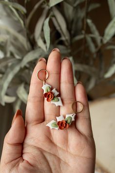 a person holding three rings in their hand with flowers on them, and one is wearing an earring