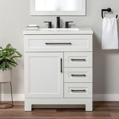 a bathroom vanity with two sinks and a mirror on the wall next to a potted plant