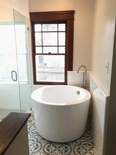 a bath tub sitting next to a window in a bathroom on top of a tiled floor