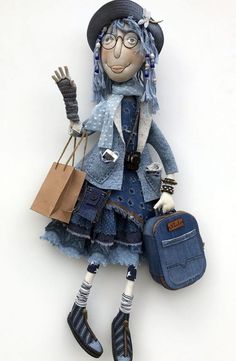 a doll with blue hair and glasses is holding a handbag in her right hand