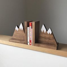 a wooden bookend with two books on it and some mountains in the back ground