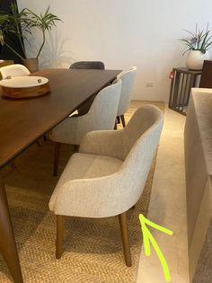 a dining room table with two chairs and a bowl on the top of it in front of a plant