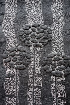 a quilted artwork with trees and dots on the bottom, in black and white