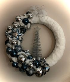 a christmas wreath with ornaments hanging on the front and side of it, next to a silver tree ornament