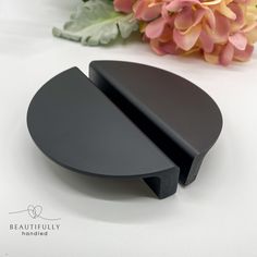 a black object sitting on top of a white table next to a bouquet of flowers