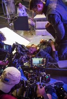 a man standing next to a woman on top of a table in front of cameras