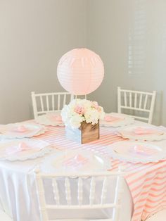 a table set up for a baby's first birthday party with pink and white decor