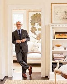 a man in a suit and tie is standing in the doorway to his living room