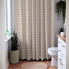 a white toilet sitting next to a shower curtain in a bathroom with wooden floors and walls