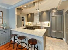 a kitchen with gray cabinets and white counter tops