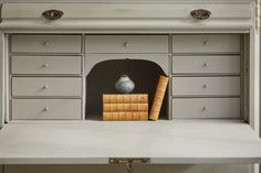 a shelf with books and a vase on it in a room that is painted white