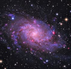 an image of a spiral galaxy in the sky with stars around it and blue, purple, and red colors