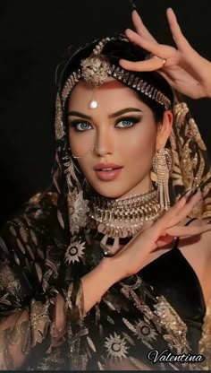 a woman with blue eyes and gold jewelry on her head is posing for the camera