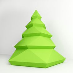 a green origami christmas tree sitting on top of a white floor next to a wall