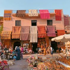 an outdoor market with lots of colorful items on display and people looking at them in the distance