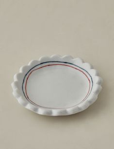 a white plate with red, blue and green stripes on the rim is sitting on a gray surface