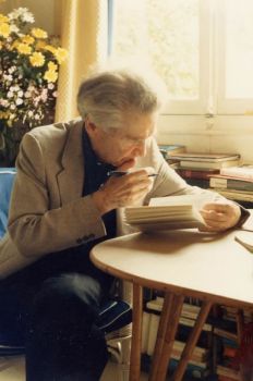 an old man sitting at a table reading a book