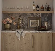 a kitchen with marble counter tops and wooden cabinetry, wine glasses on the shelves