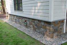 the side of a house with grass and rocks