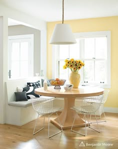 a dining room with yellow walls and white chairs