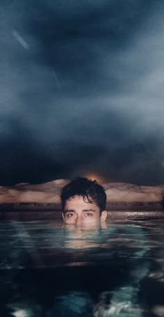 a man swimming in the water under a cloudy sky