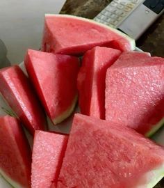 slices of watermelon are on a plate with a remote control in the background