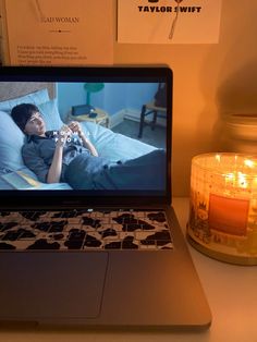 a laptop computer sitting on top of a desk next to a candle and some pictures