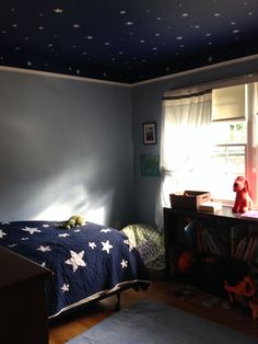 a child's bedroom with blue walls and white stars painted on the ceiling above