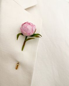 a pink flower is placed on the lapel of a white suit