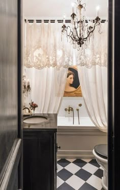 a bathroom with black and white checkered flooring, a chandelier and a bathtub