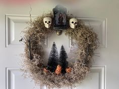 a halloween wreath with skulls and trees on the front door is decorated with fake grass