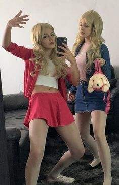 two young women are standing in front of a mirror and one is holding a cell phone