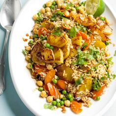 a white plate topped with rice and veggies on top of a blue table