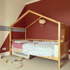 a child's bed in the corner of a room with red walls and carpet