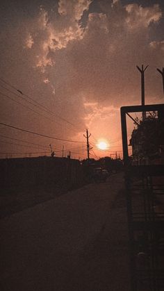 the sun is setting behind power lines and telephone poles in an alley way with no cars on it