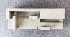 a model of a house made out of concrete blocks on a gray carpeted floor