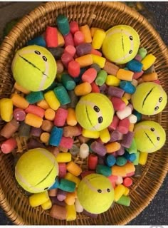 a basket filled with lots of different colored candies next to two tennis balls on top of each other