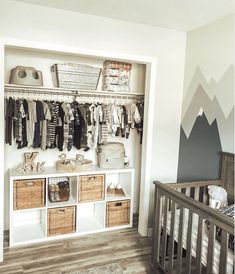 a baby's room with mountains painted on the wall and an open crib