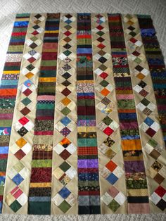 the quilts are all different colors and patterns on the tablecloth, which is laid out in rows