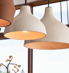 three lamps hanging from the ceiling in a room with large windows and potted plants