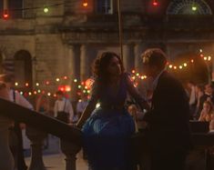 a man and woman standing next to each other in front of a building at night