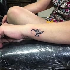 a person with a small tattoo on their arm sitting on top of a chair in front of a table