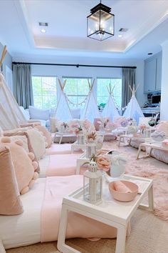 a living room filled with lots of furniture and pink pillows on top of white tables