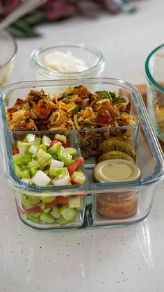 several containers filled with food sitting on top of a table next to other dishes and utensils