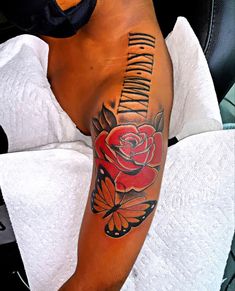 a man's arm with a rose and butterfly tattoo on it, sitting in a chair